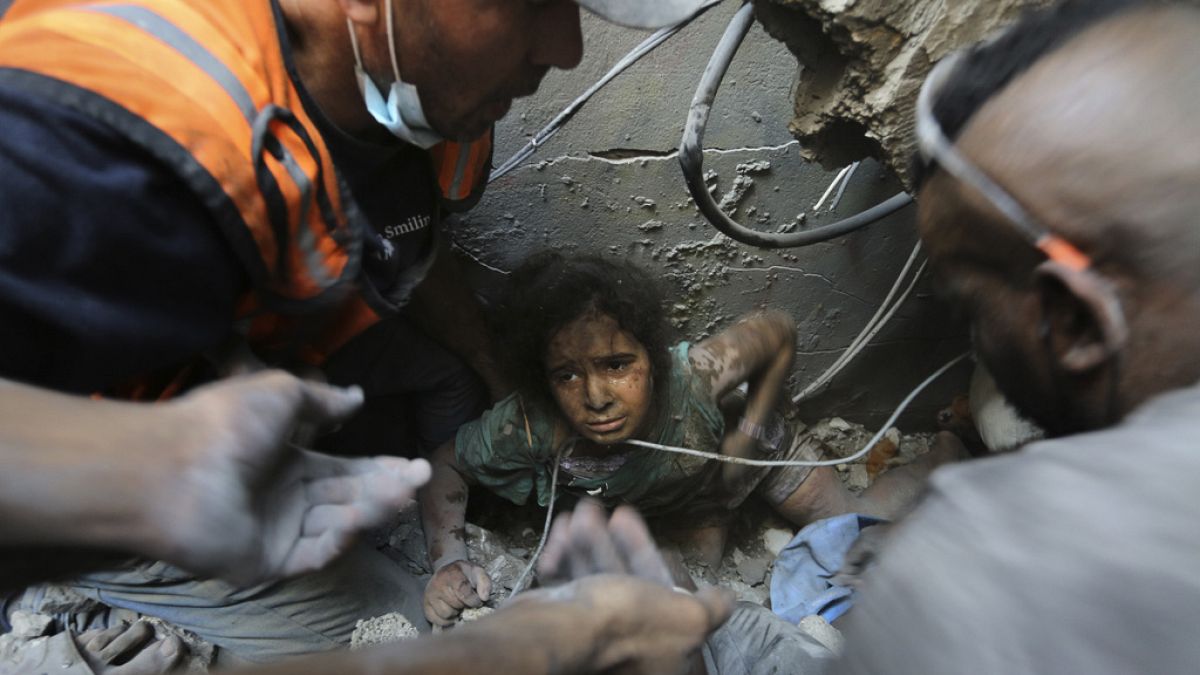 Palestinianos tentam tirar uma menina dos escombros de edifício destruído pelos ataques de Israel ao campo de refugiados de Jabalia, na Faixa de Gaza