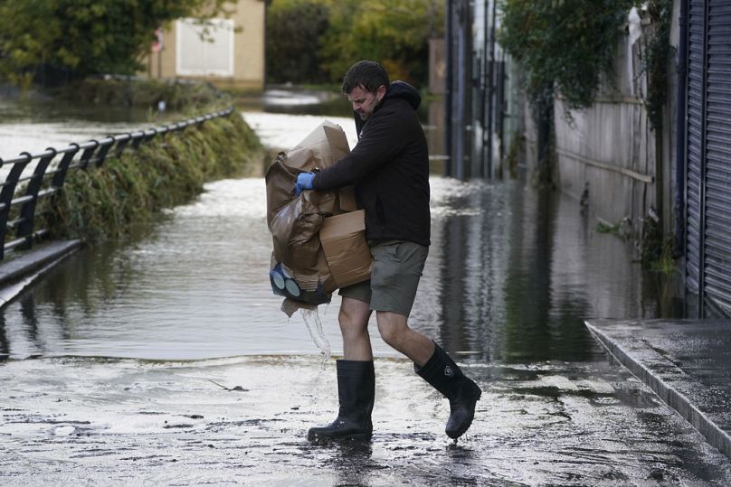 Michael Nugent, the owner of Nugelato ice cream cleans up his shop in Sugar Island, Newry Town, Northern Ireland, Wednesday, Nov. 1, 2023, amid heavy rainfall.