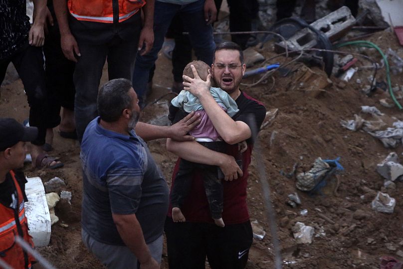 A Palestinian man cries while holding a dead child who was found under the rubble of a destroyed building following Israeli airstrikes in Nusseirat refugee camp on Tuesday