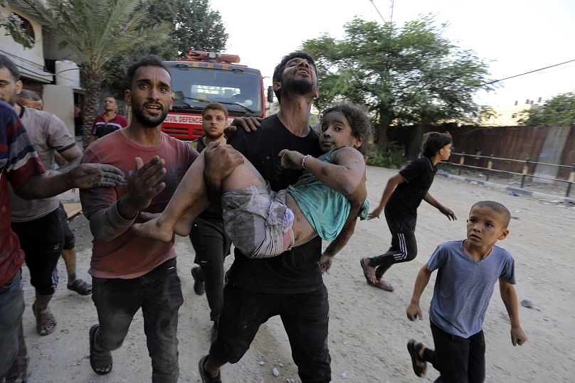 Palestinians carry a wounded girl after being rescued from under the rubble of buildings that were destroyed by Israeli airstrikes in Jabaliya refugee camp on Wednesday