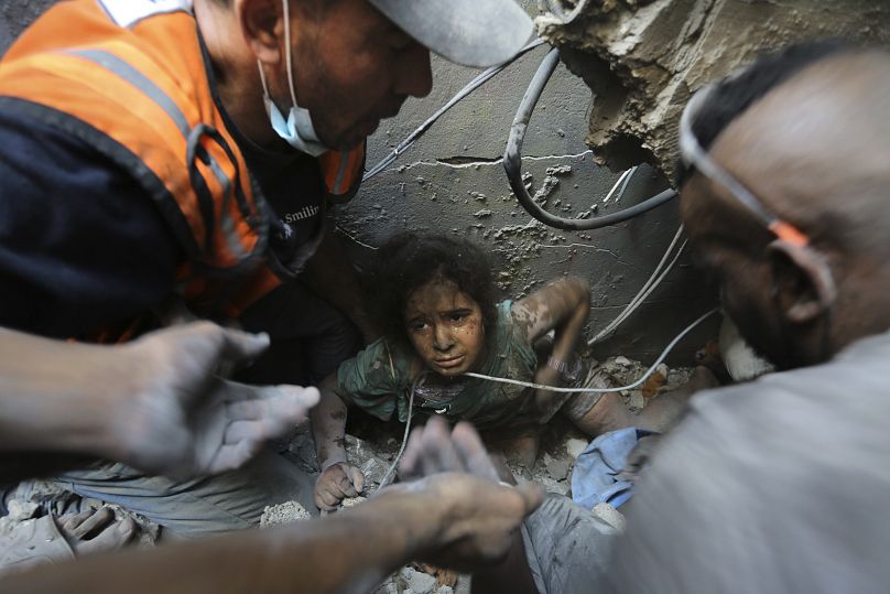 Palestinians try to pull a girl out of the rubble of a building that was destroyed by Israeli airstrikes in Jabaliya refugee camp, northern Gaza Strip on Wednesday