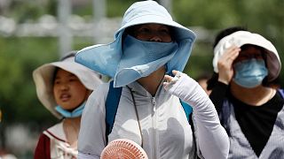 1 Temmuz 2023, Pekin, Çin'de bir sokakta sıcak hava dalgası yürüyüşü sırasında güneşten korunma ekipmanı giyen insanlar.