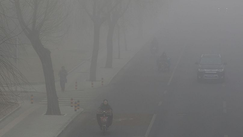 People drive and ride amid the smog in Beijing, China, 14 February 2017.