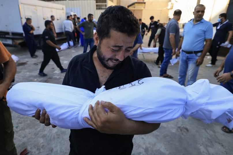 A Palestinian man reacts while holding the body of a relative killed following Israeli bombardment on October 31, 2023.