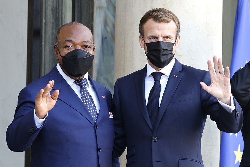 France's President Emmanuel Macron (R) and President of Gabon Ali Bongo Ondimba wave to the press from the stairs of the Elysee Palace, in Paris on November 12, 2021.