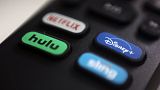 The logos for streaming services Netflix, Hulu, Disney Plus and Sling TV on a remote control.