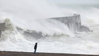 Una persona de pie en la playa, mientras una ola se estrella contra el muro del puerto de Newhaven, mientras la tormenta Ciaran azota la costa inglesa, en Newhaven, Gran Bretaña.