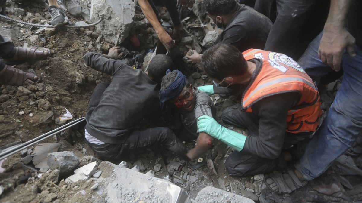 Des sauveteurs palestiniens tentent de sortir un blessé des décombres d'un bâtiment détruit par une frappe aérienne israélienne dans le camp de réfugiés de Bureij