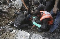 Des sauveteurs palestiniens tentent de sortir un blessé des décombres d'un bâtiment détruit par une frappe aérienne israélienne dans le camp de réfugiés de Bureij