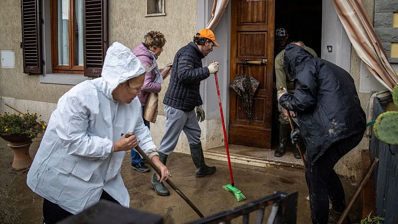 People clean a flooded house in Montemurlo, near Prato, after heavy rain last night, on November 3, 2023.