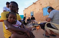 أشخاص يجلسون حول الطعام في مدرسة تم تحويلها إلى ملجأ على الحدود السودانية 
