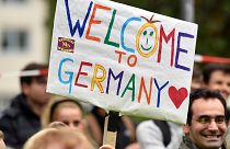 Des personnes accueillent des réfugiés avec une banderole indiquant "Bienvenue en Allemagne" à Dortmund, Allemagne, dimanche 6 septembre 2015.