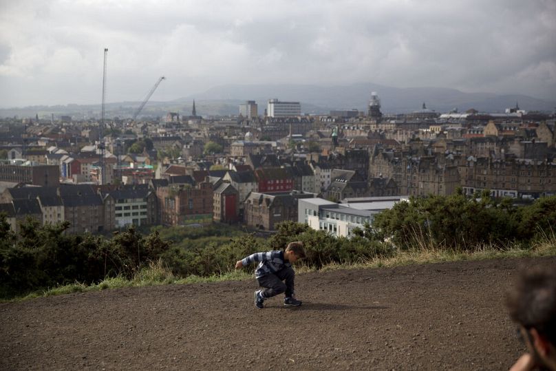 A young tourist with his family plays on Edinburgh's Calton Hill.