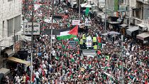 أشخاص يتجمعون رافعين الأعلام الأردنية والفلسطينية في مسيرة تضامنية مع الفلسطينيين في قطاع غزة
