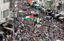 أشخاص يتجمعون رافعين الأعلام الأردنية والفلسطينية في مسيرة تضامنية مع الفلسطينيين في قطاع غزة