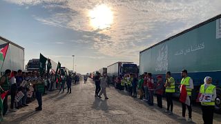 متطوعون وشاحنات تحمل المساعدات الإنسانية لغزة تقف على معبر رفح بين قطاع غزة ومصر