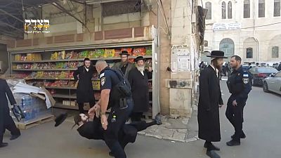 شرطي إسرائيلي يدفع يهوديا متدينا على الأرض خلال وقفة تضامنية مع الفلسطينيين