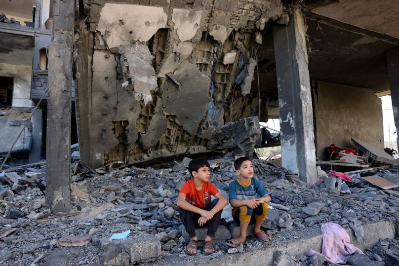 Children sit amid the rubble of a building in the aftermath of an Israeli strike in Rafah in the southern Gaza Strip on Friday