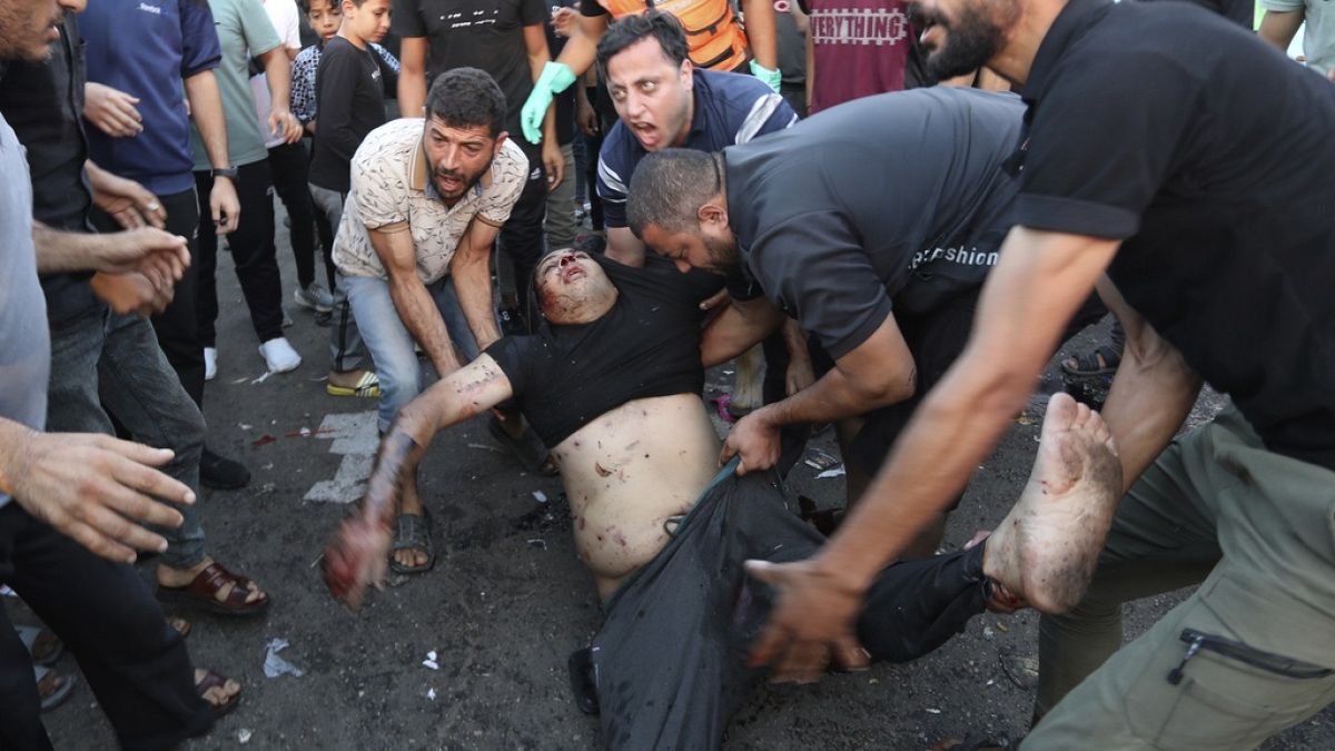 An injured Palestinian man is carried from the ground following an Israeli airstrike outside the entrance of the al-Shifa hospital in Gaza City.