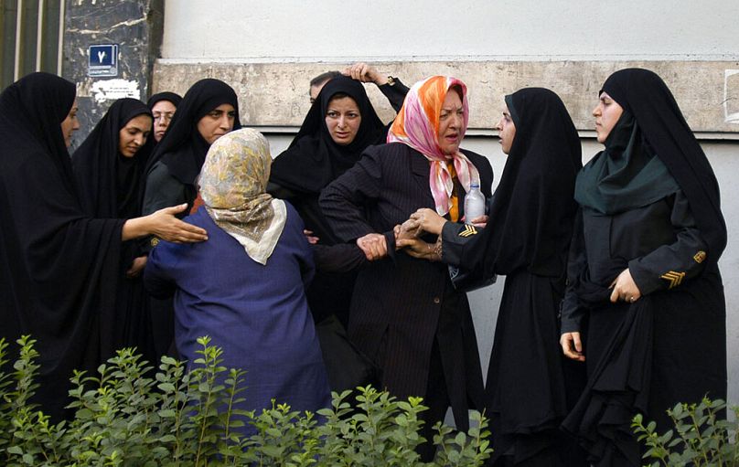İranlı kadın polis memurları, protestolar sırasında kadınları gözaltına almak isterken (arşiv)