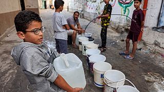 Un niño recoge agua con un bidón en Gaza