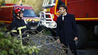 France's President Emmanuel Macron (R) speaks with a firefighter during a visit in a region hit by Storm Ciaran in Plougastel-Daoulas, western France