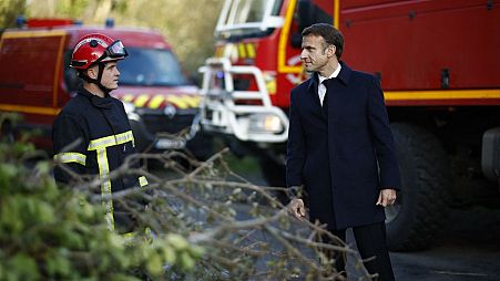 France's President Emmanuel Macron (R) speaks with a firefighter during a visit in a region hit by Storm Ciaran in Plougastel-Daoulas, western France