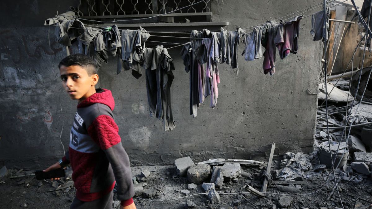 Un garçon regarde les gens chercher des survivants et les corps des victimes dans les bâtiments détruits par les bombardements israéliens, à Al-Maghazi, dans la bande de Gaza, dimanche.