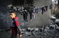 Un garçon regarde les gens chercher des survivants et les corps des victimes dans les bâtiments détruits par les bombardements israéliens, à Al-Maghazi, dans la bande de Gaza, dimanche.