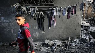 A boy looks as people search for survivors and the bodies of victims through buildings that were destroyed during Israeli bombardment, in Al-Maghazi, Gaza Strip on Sunday