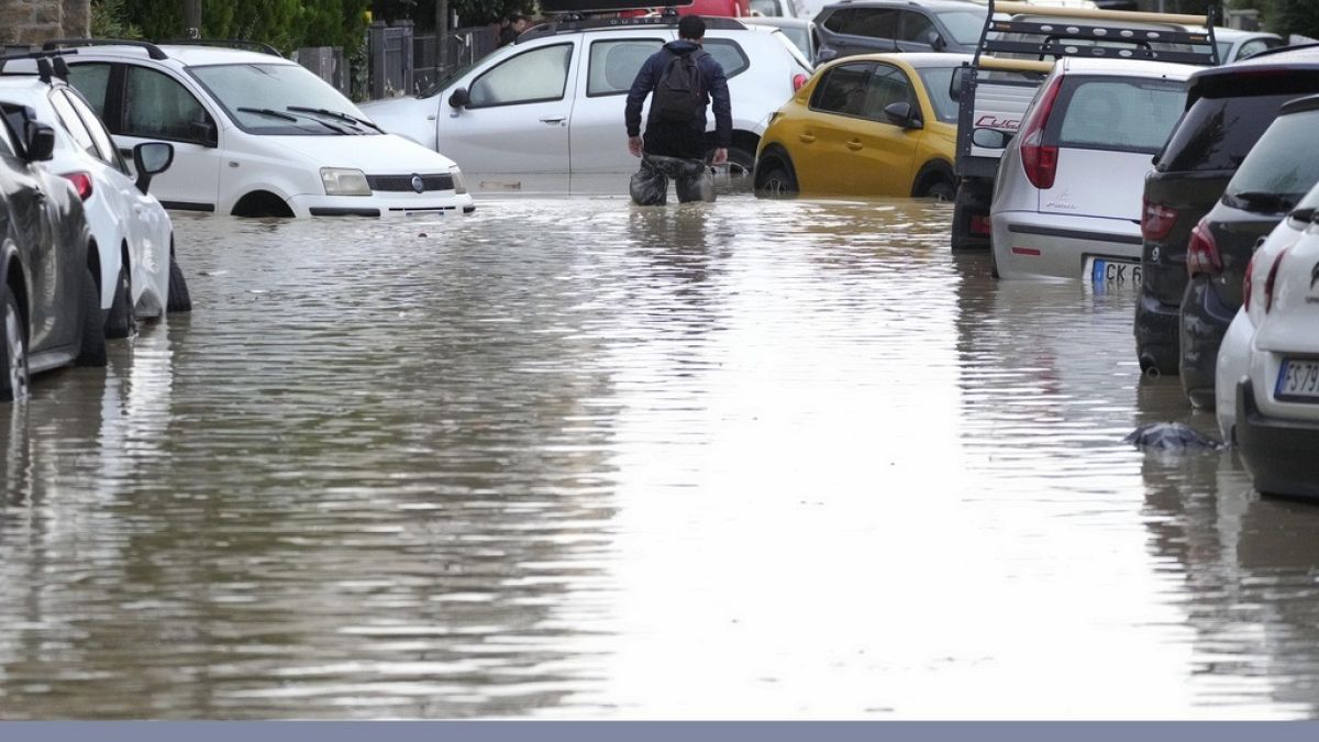 A man makes is way on a flooded street.