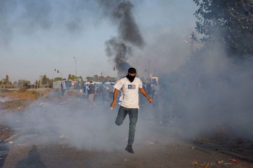 A protestor runs amid the tear gas fired by Turkish anti-riot police during a Pro-Palestinian demonstration against US secretary of state's visit to Turkey
