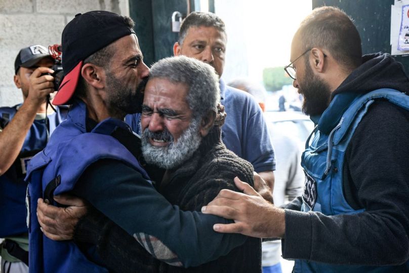 Palestinian cameraman Mohammed Alaloul (L) hugs his father after two of his children and his brother were killed in an Israeli strike on the Al-Maghazi refugee camp