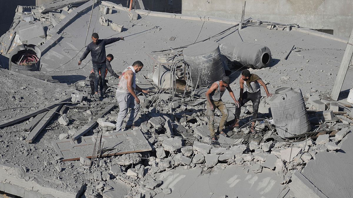 Palestinianos procuram sobreviventes após bombardeamento edo campo de Nusseirat, em Gaza