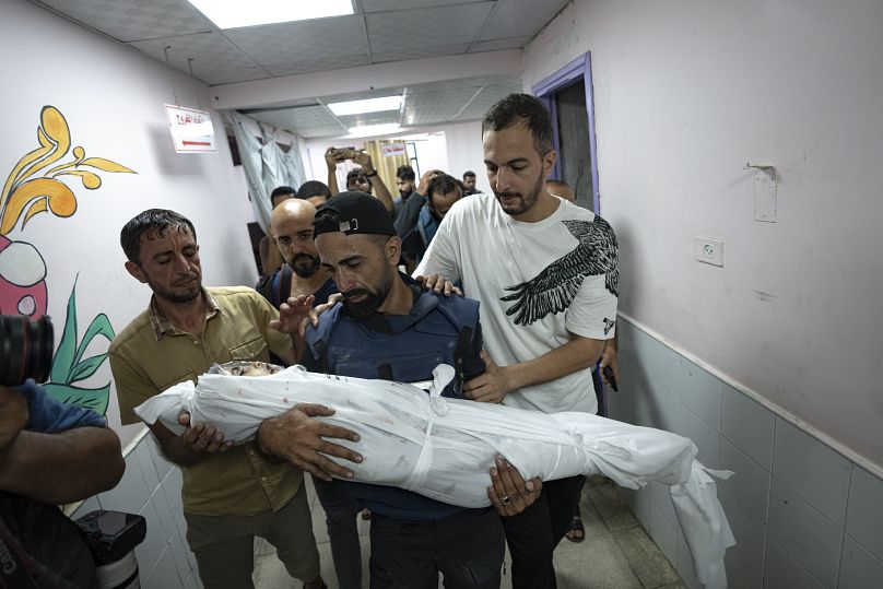 الصحفي الفلسطيني محمد العالول يحمل جثمان طفله الذي استشهد في القصف الإسرائيلي على قطاع غزة، في مستشفى دير البلح، الأحد 5 نوفمبر 2023