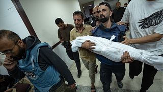 المصور الفلسطيني محمد العالول يحمل جثمان أحد أطفاله