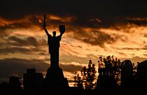 A photograph shows the Motherland monument silhouetted against a cloudy sky at sunset in Kyiv on October 28, 2023.