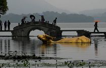 پل سنگی در کنار مجسمه طلایی رنگ گاو در چین