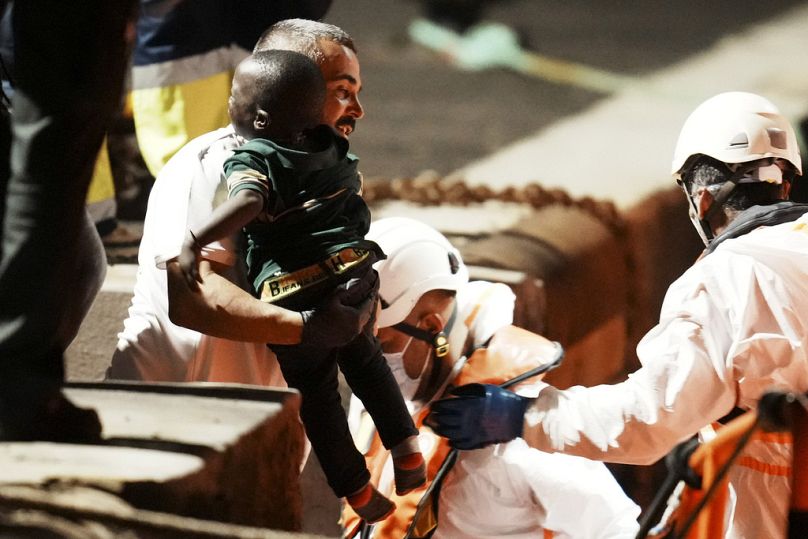 A boy is held by a rescue worker at the port in La Restinga, on the Canary island of El Hierro on Saturday, Nov. 4, 2023.