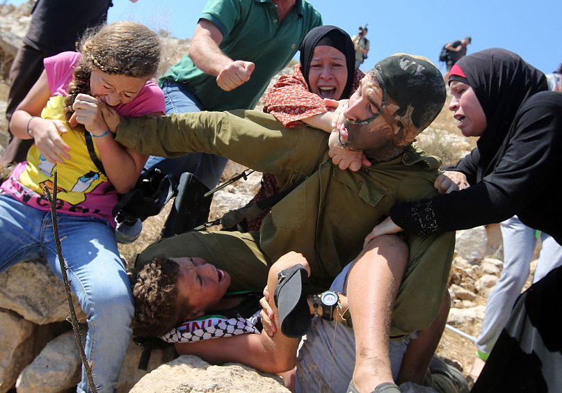 عهد تمیمی و خانواده‌اش در حال نجات دادن پسر فلسطینی از دستان سرباز اسرائیلی