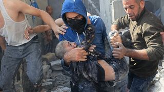 فلسطيني يحمل طفلا من تحت أنقاض مبنى مدمر في أعقاب غارة جوية إسرائيلية