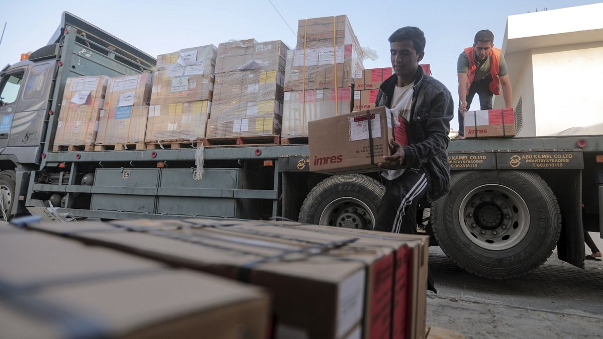 Palestinianos descarregam caixas de medicamentos de um camião que chegou ao Complexo Médico Nasser, como parte do lote de ajuda que entrou em Gaza pela passagem de Rafah, 23 de outubro de 2023.