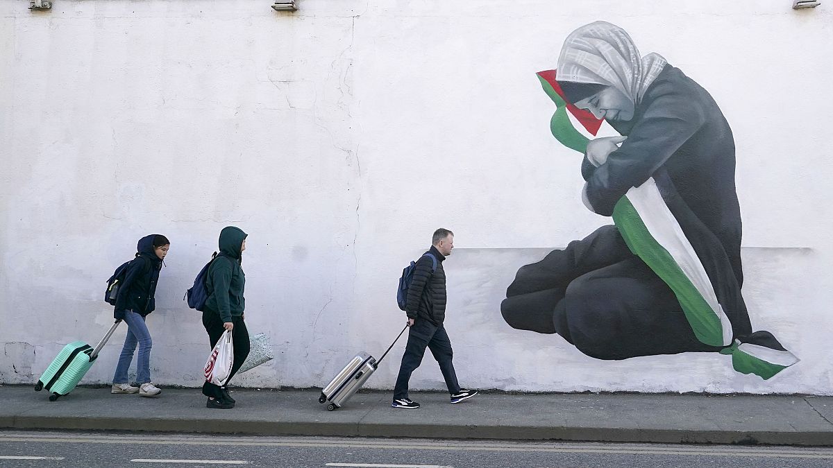 Des personnes passent devant une peinture murale pro-palestinienne réalisée par l'artiste Emmalene Blake dans le quartier de Harold's Cross à Dublin, en Irlande.