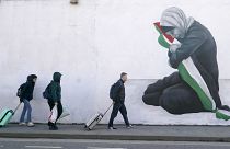 Emberek sétálnak Emmalene Blake művész palesztinbarát falfestménye mellett Dublin Harold's Cross negyedében, Írországban.