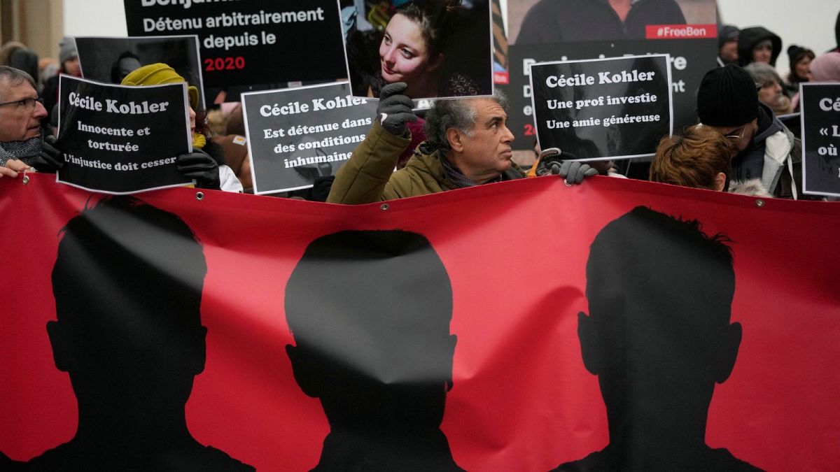 مردی با پرتره‌ای از سیسیل کوهلر در جریان اعتراضات در پاریس، ۲۸ ژانویه ۲۰۲۳