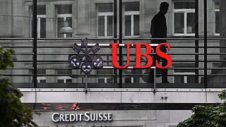  n чиновник на мултинационална капиталова банка UBS минава около табела на швейцарския банков колос UBS над табела на Credit Suisse в Цюрих на 31 август 2023 година 