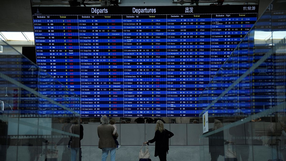 Travellers looking at the departure information panel of the Terminal 2 of the Roissy-Charles de Gaulle airport.
