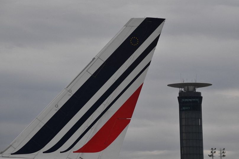 The tail of an Air France airplane and an air traffic control tower at the Roissy-Charles de Gaulle airport.