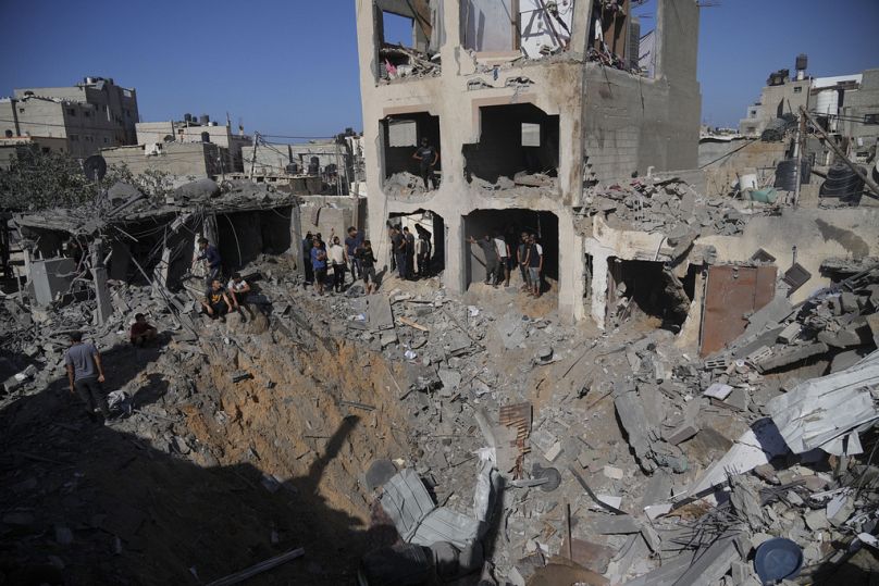 Palestinians look at buildings destroyed in the Israeli bombardment in the morgue in Deir al Balah, Gaza Strip, Tuesday, Nov. 7, 2023.