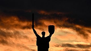 A photograph shows the Motherland monument silhouetted against a cloudy sky at sunset in Kyiv on October 28, 2023.
